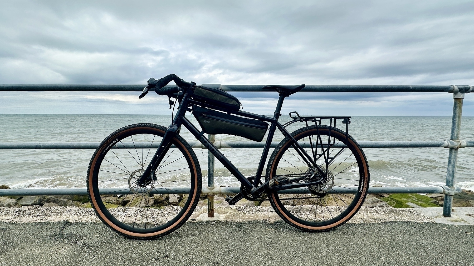 a gravel bike leaning against a barrier beside the sea