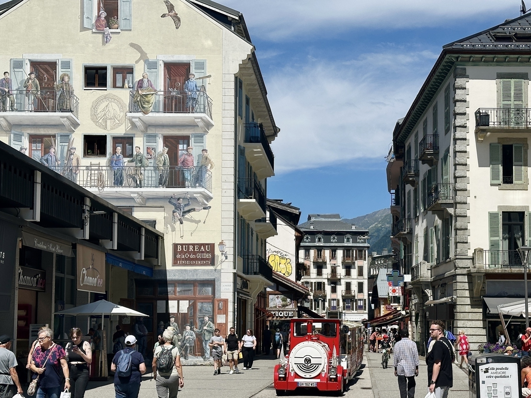 A picturesque mountain town features charming buildings with a snowy mountain backdrop under a clear blue sky.